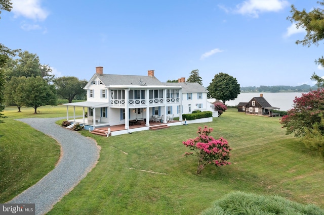 rear view of property with a sunroom and a lawn