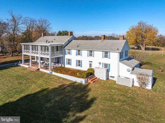 back of property with a patio area, a sunroom, and a lawn