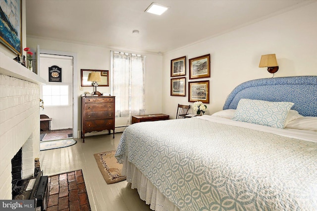 bedroom with multiple windows, light hardwood / wood-style flooring, ornamental molding, and a fireplace