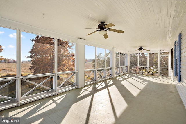 unfurnished sunroom featuring a rural view and ceiling fan