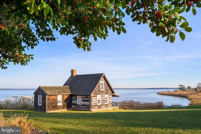 view of outdoor structure with a lawn and a water view