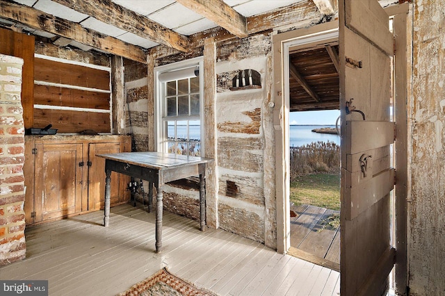 doorway to outside with light wood-type flooring, beam ceiling, and a water view