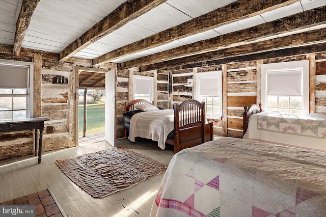 bedroom with beam ceiling, multiple windows, and light hardwood / wood-style flooring