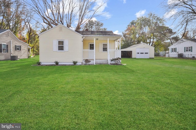 rear view of property featuring a yard, covered porch, central AC unit, a garage, and an outbuilding