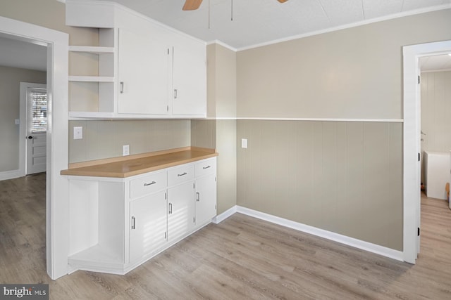 kitchen with wooden walls, light hardwood / wood-style flooring, ceiling fan, and ornamental molding