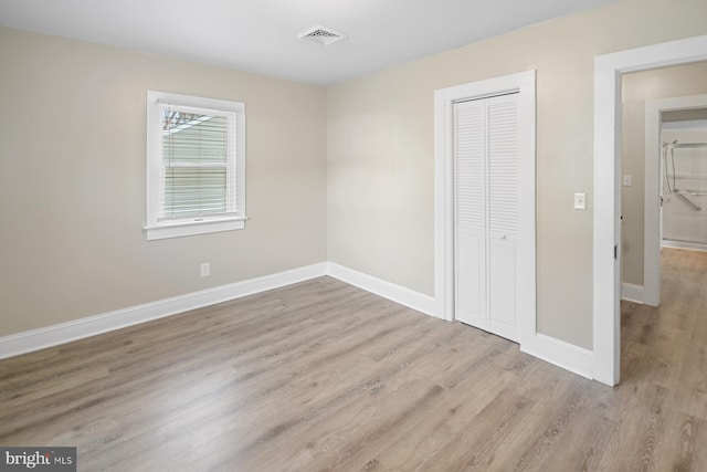 unfurnished bedroom featuring light wood-type flooring and a closet