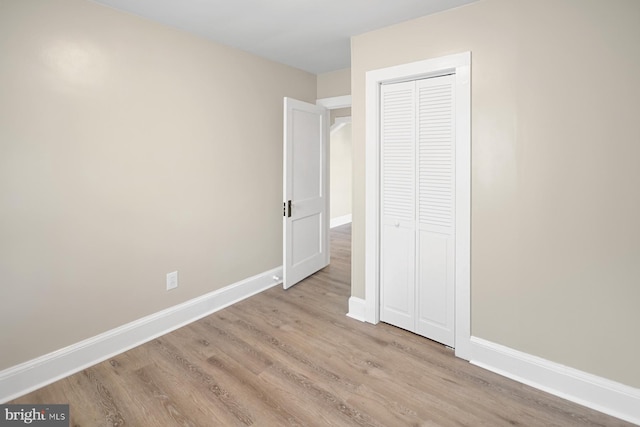 unfurnished bedroom with light hardwood / wood-style flooring and a closet