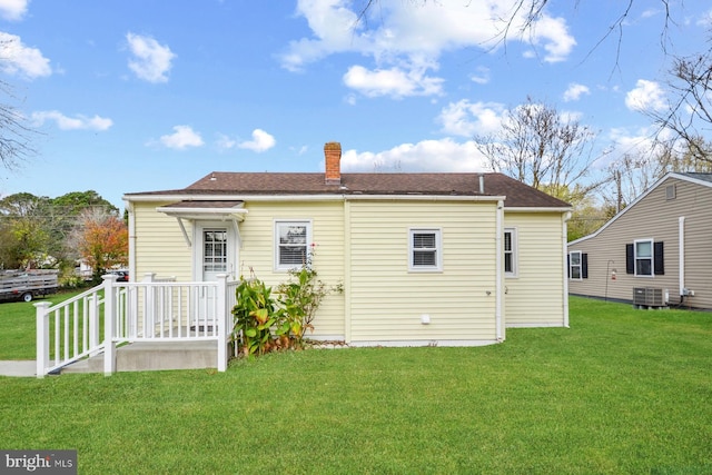 back of property with central AC unit and a lawn