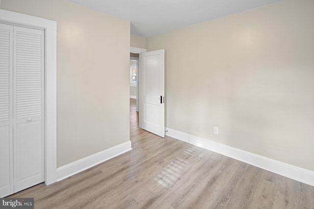 unfurnished bedroom with light wood-type flooring and a closet