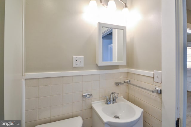 bathroom with sink, tile walls, and toilet