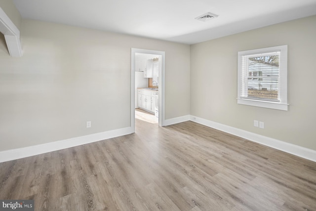 spare room with sink and light hardwood / wood-style floors