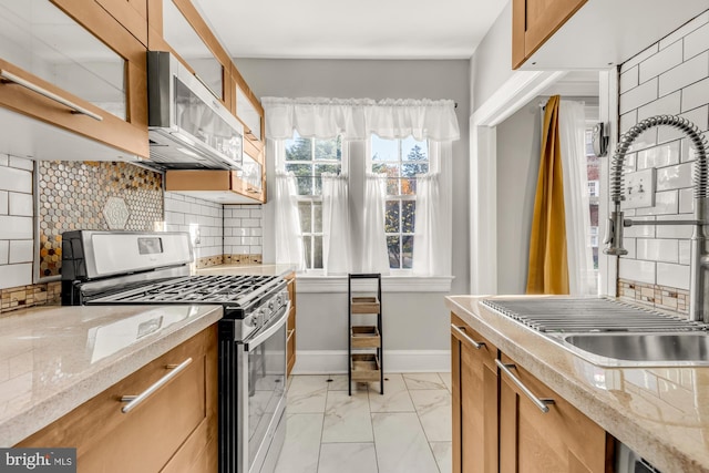 kitchen featuring light stone countertops, stainless steel appliances, tasteful backsplash, and sink