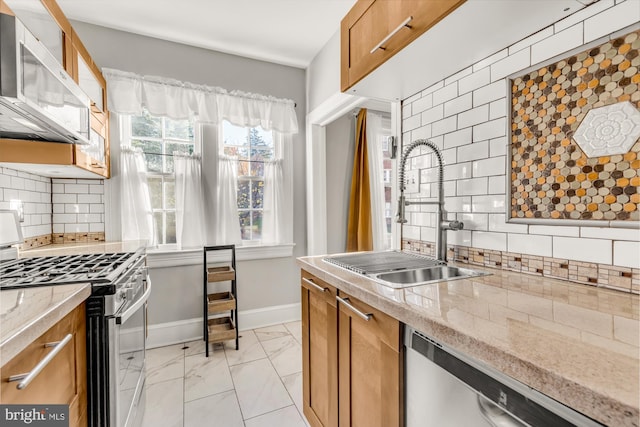 kitchen featuring backsplash, light stone countertops, sink, and appliances with stainless steel finishes