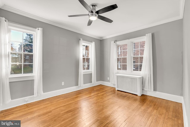 empty room featuring radiator, ceiling fan, hardwood / wood-style floors, and ornamental molding