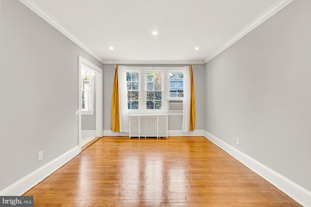 empty room with radiator heating unit, light wood-type flooring, cooling unit, and crown molding