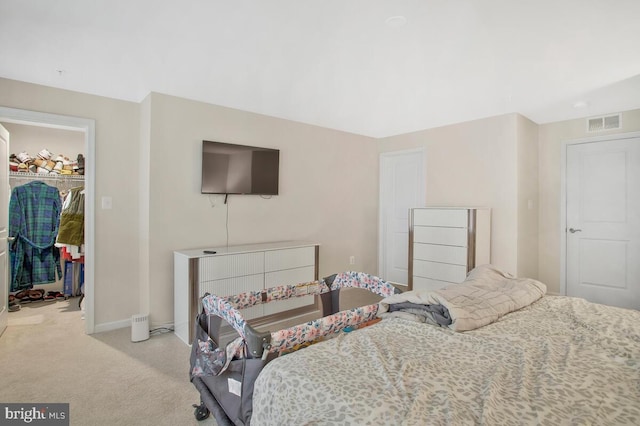 carpeted bedroom with a walk in closet and a closet