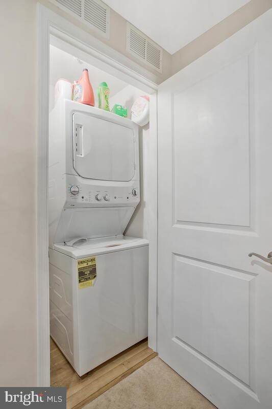 laundry area featuring light wood-type flooring and stacked washing maching and dryer