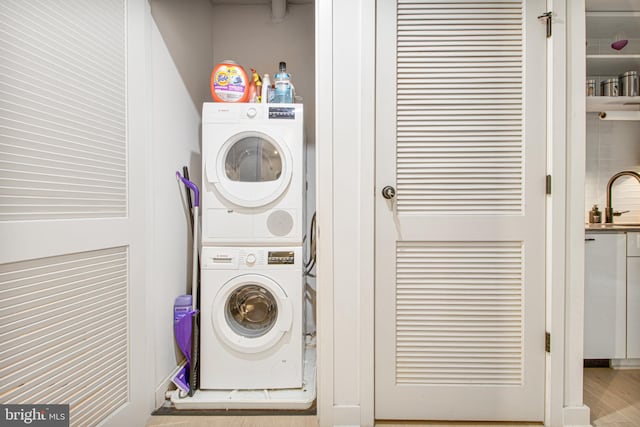 washroom featuring stacked washer and dryer, light hardwood / wood-style floors, and sink