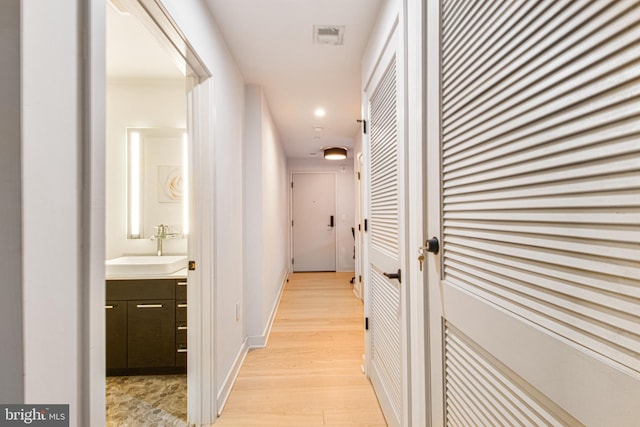 hall with light hardwood / wood-style floors and sink