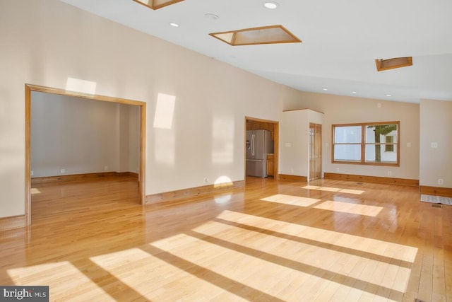 spare room featuring light wood-type flooring and vaulted ceiling