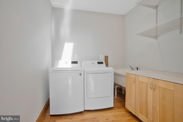 clothes washing area with cabinets, separate washer and dryer, and light hardwood / wood-style flooring