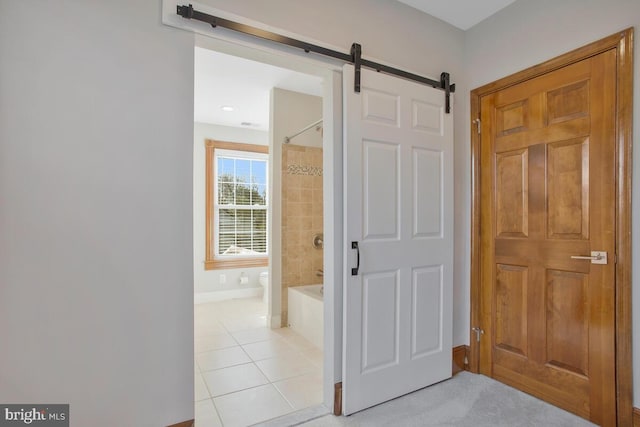 hallway featuring a barn door and light tile patterned flooring