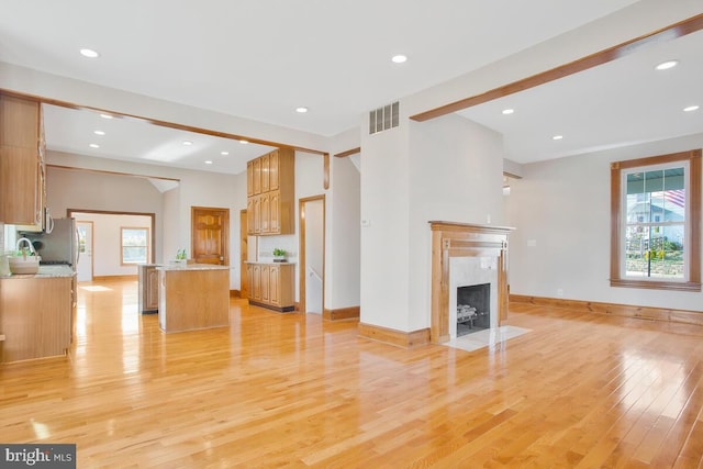 unfurnished living room with sink, light hardwood / wood-style flooring, and a fireplace