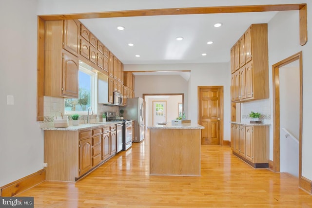 kitchen with light hardwood / wood-style floors, sink, appliances with stainless steel finishes, and tasteful backsplash