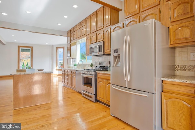 kitchen with backsplash, sink, stainless steel appliances, and light hardwood / wood-style flooring