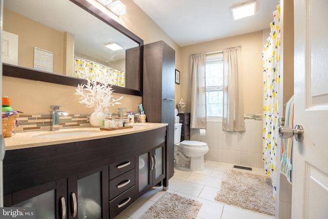 bathroom featuring tile patterned flooring, vanity, toilet, and tile walls