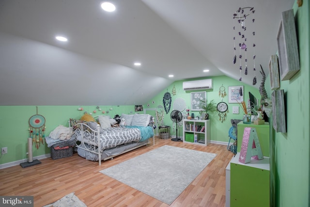 bedroom featuring a wall mounted air conditioner, hardwood / wood-style flooring, and vaulted ceiling