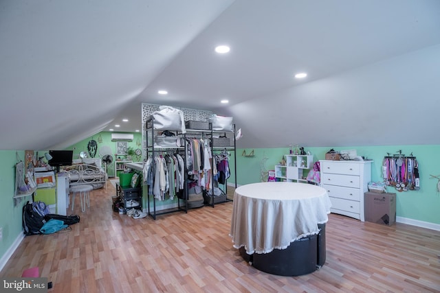 bedroom with light hardwood / wood-style floors, lofted ceiling, and a wall mounted AC