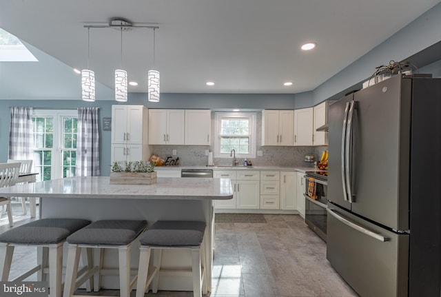 kitchen with appliances with stainless steel finishes, backsplash, decorative light fixtures, and white cabinetry