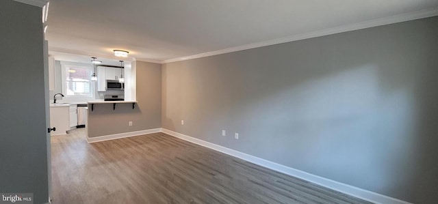 spare room with hardwood / wood-style flooring, ornamental molding, and sink