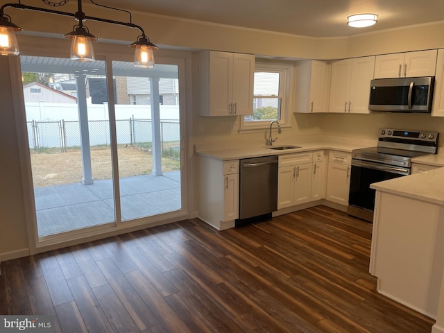 kitchen featuring pendant lighting, dark wood-type flooring, white cabinets, sink, and appliances with stainless steel finishes