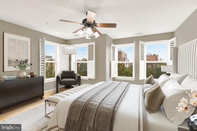 bedroom featuring ceiling fan, light hardwood / wood-style flooring, and multiple windows