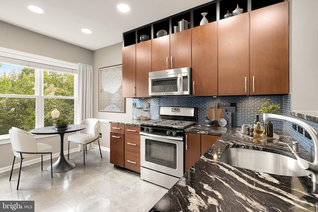 kitchen with decorative backsplash, sink, dark stone counters, and appliances with stainless steel finishes