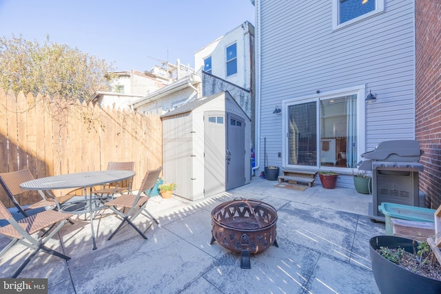 view of patio / terrace featuring grilling area, a fire pit, and a storage shed