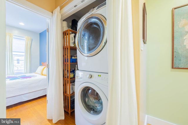 washroom featuring stacked washer / dryer and light hardwood / wood-style flooring