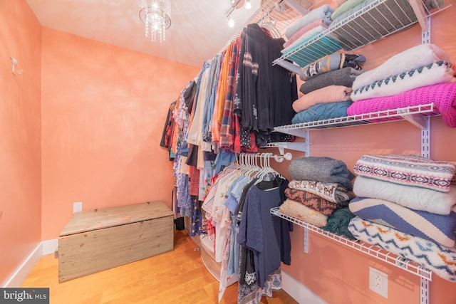 spacious closet featuring hardwood / wood-style floors and a notable chandelier