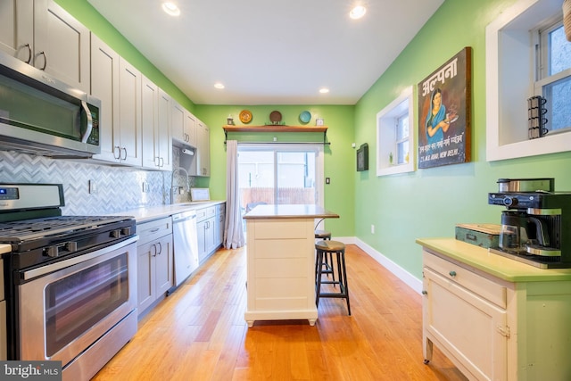 kitchen with a breakfast bar, sink, light hardwood / wood-style floors, appliances with stainless steel finishes, and a kitchen island