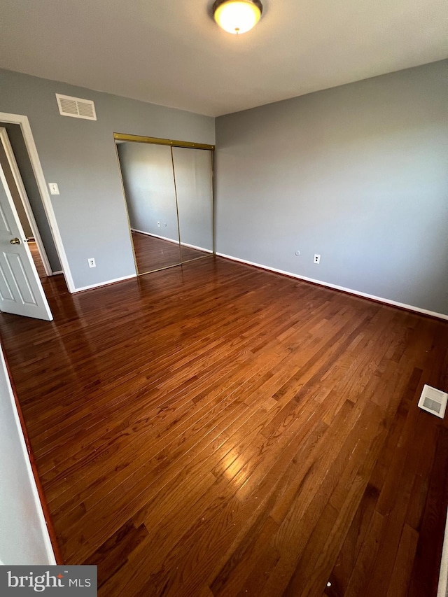 unfurnished bedroom featuring dark wood-type flooring and a closet