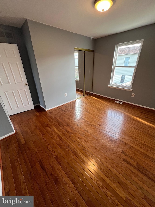 unfurnished bedroom featuring a closet and hardwood / wood-style flooring