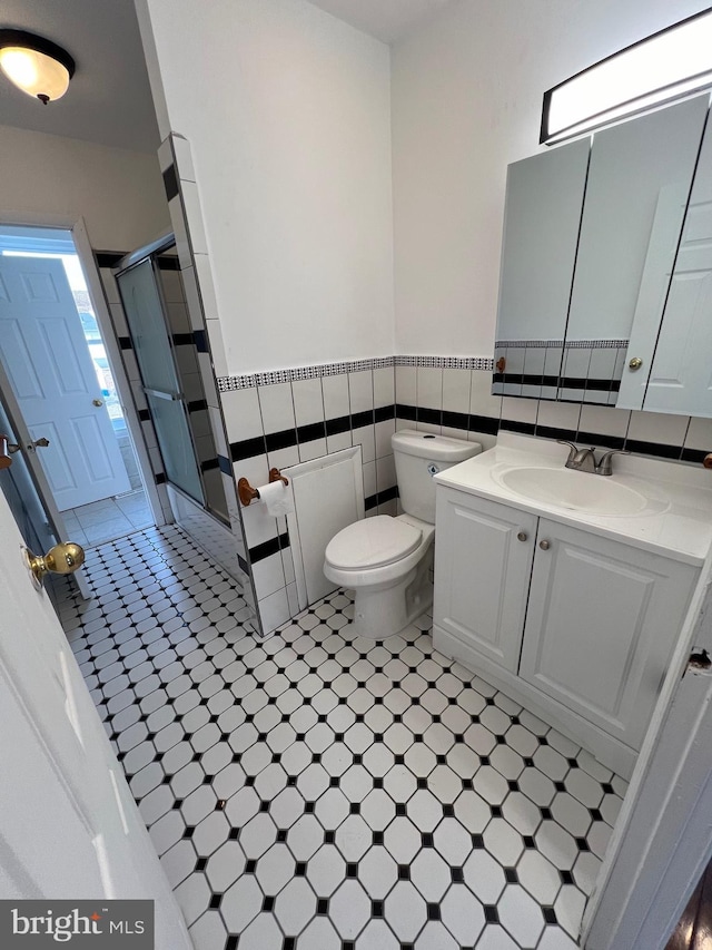 bathroom featuring toilet, vanity, tile walls, and walk in shower