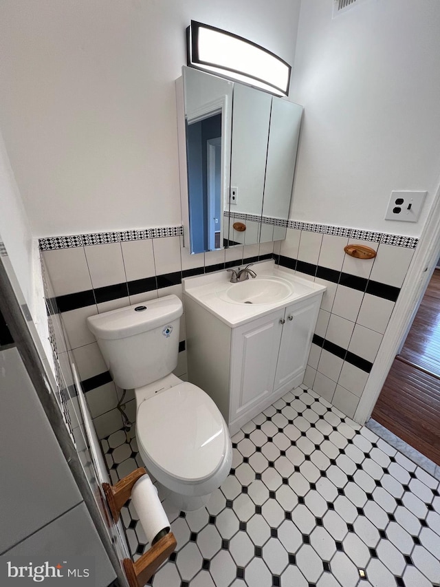 bathroom featuring vanity, toilet, and tile walls