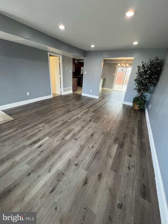 unfurnished living room with hardwood / wood-style floors and an inviting chandelier