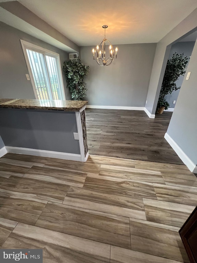 unfurnished dining area with dark hardwood / wood-style flooring and a notable chandelier