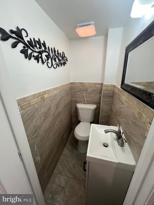 bathroom featuring vanity, tile walls, and toilet