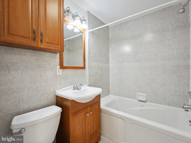 full bathroom featuring tiled shower / bath, vanity, toilet, and tile walls