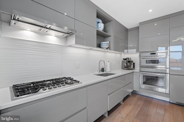 kitchen with sink, backsplash, extractor fan, gray cabinets, and appliances with stainless steel finishes